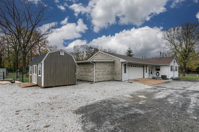 view of front facade featuring central AC, a storage shed, and a garage