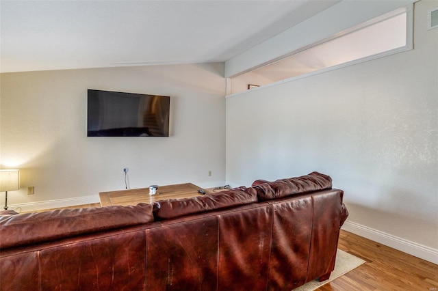 living room featuring lofted ceiling with beams and light hardwood / wood-style flooring