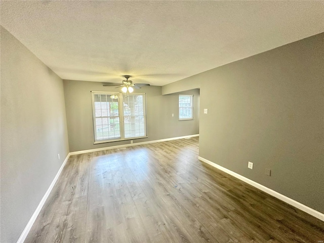 empty room with a wealth of natural light, ceiling fan, a textured ceiling, and hardwood / wood-style flooring