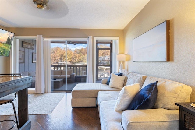 living room featuring ceiling fan and dark wood-type flooring