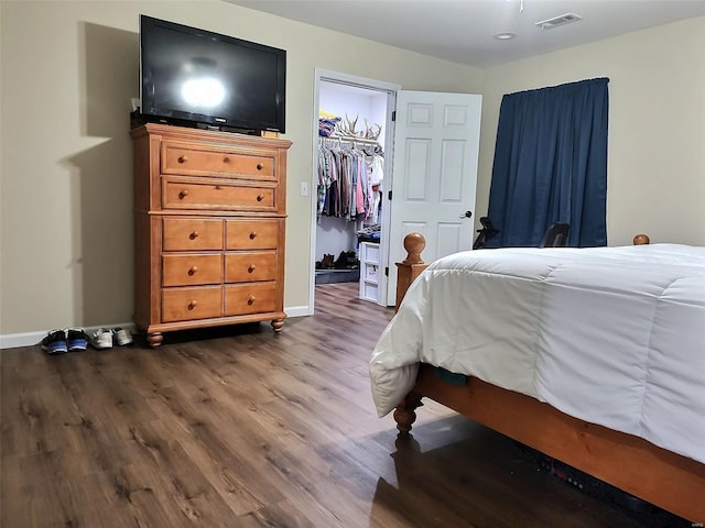 bedroom with a spacious closet, a closet, and hardwood / wood-style flooring