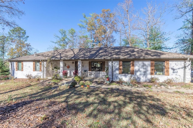 ranch-style home featuring covered porch and a front lawn