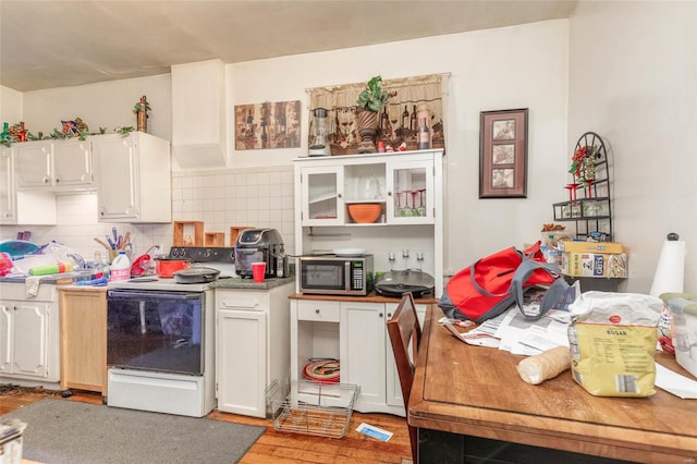 kitchen with white cabinets, hardwood / wood-style floors, tasteful backsplash, and white electric stove