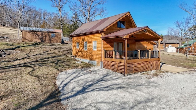 exterior space with metal roof, an outbuilding, a wooden deck, and a shed