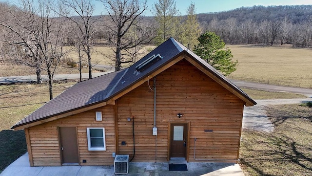 exterior space featuring central air condition unit and a wooded view