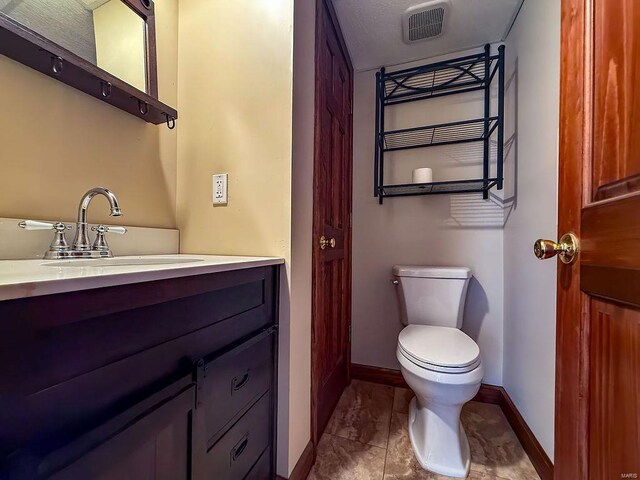 half bathroom featuring visible vents, toilet, vanity, and baseboards