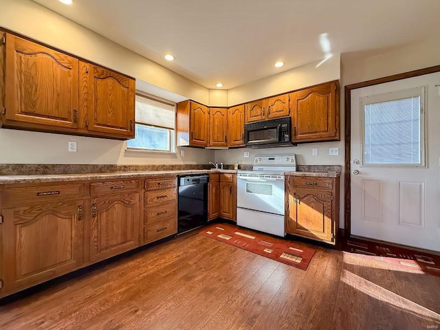 kitchen featuring recessed lighting, brown cabinets, black appliances, and dark wood-style flooring