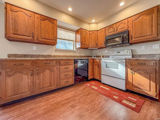 kitchen featuring recessed lighting, light wood-style floors, black appliances, and brown cabinetry