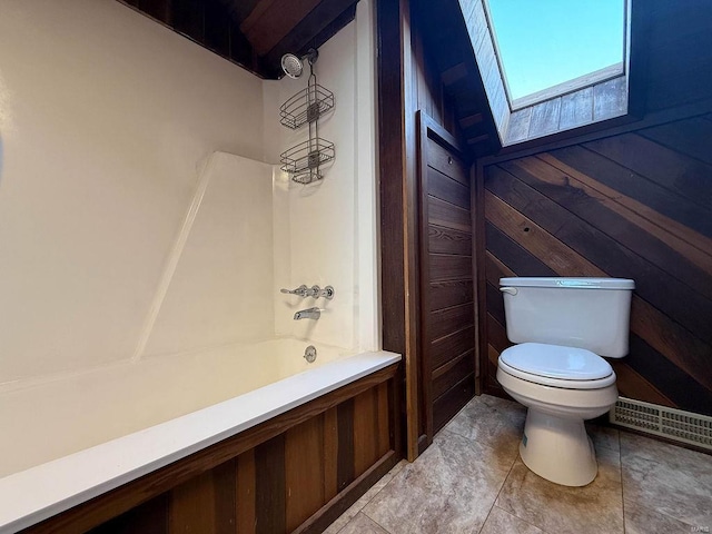 full bathroom featuring a skylight, toilet, and shower / washtub combination