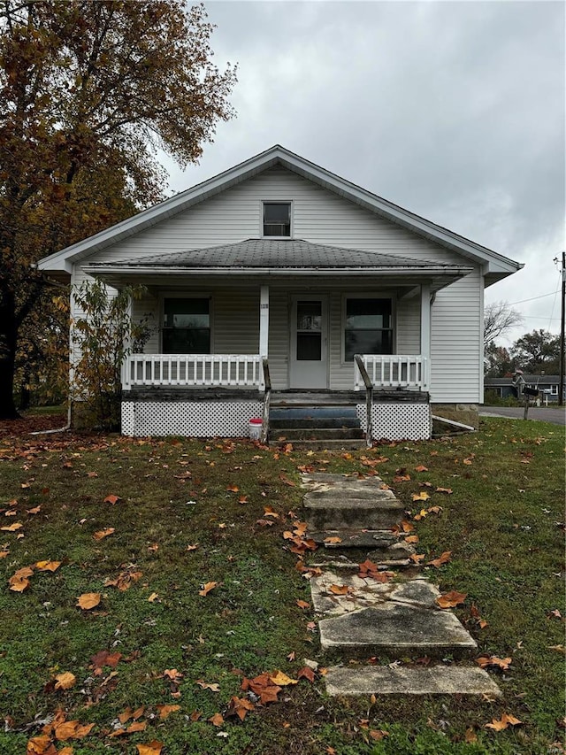 bungalow featuring covered porch and a front yard