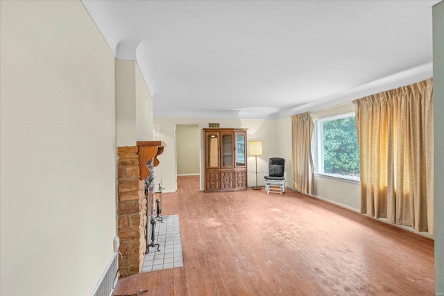 unfurnished living room with a stone fireplace and hardwood / wood-style flooring