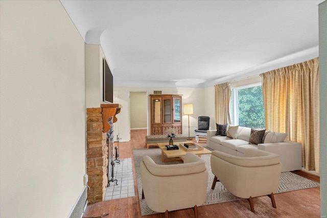 living room with a stone fireplace and light hardwood / wood-style flooring