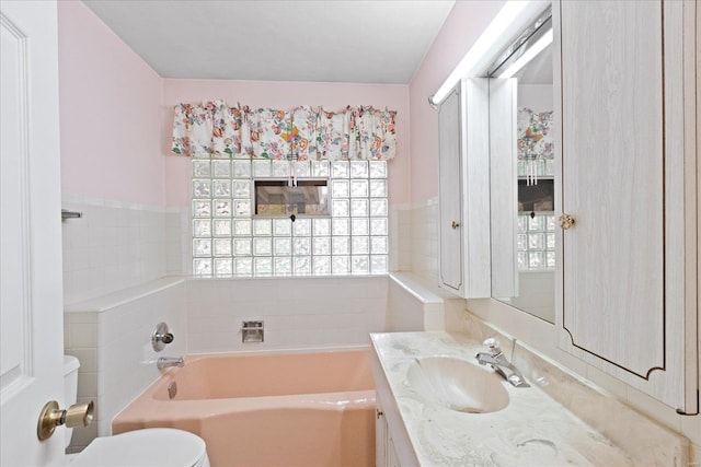 bathroom with vanity, a bathtub, a wealth of natural light, and tile walls