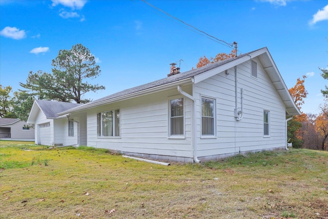 view of side of home with a garage and a lawn