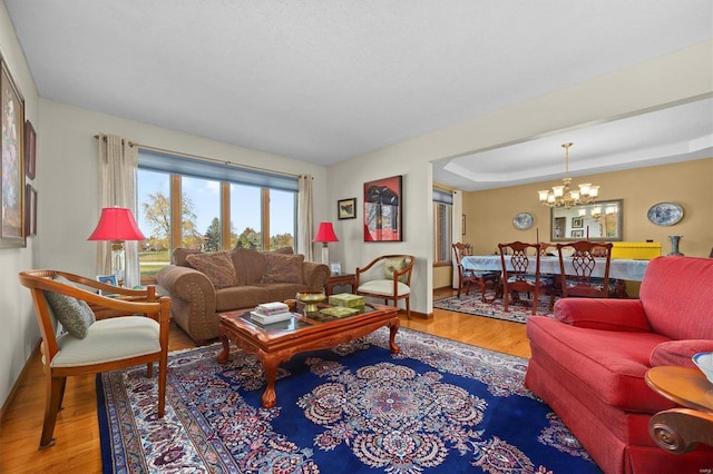 living room featuring a tray ceiling, hardwood / wood-style floors, and a notable chandelier