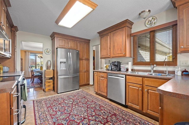 kitchen featuring light tile patterned floors, a textured ceiling, stainless steel appliances, and sink