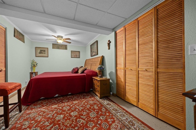 bedroom featuring a drop ceiling, ceiling fan, and ornamental molding