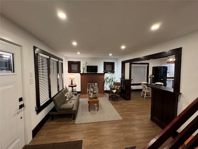 living room featuring dark wood-type flooring and a brick fireplace