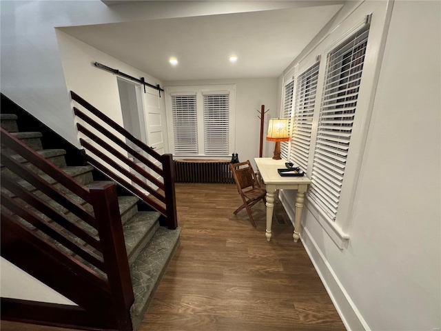 home office with a barn door and dark hardwood / wood-style flooring