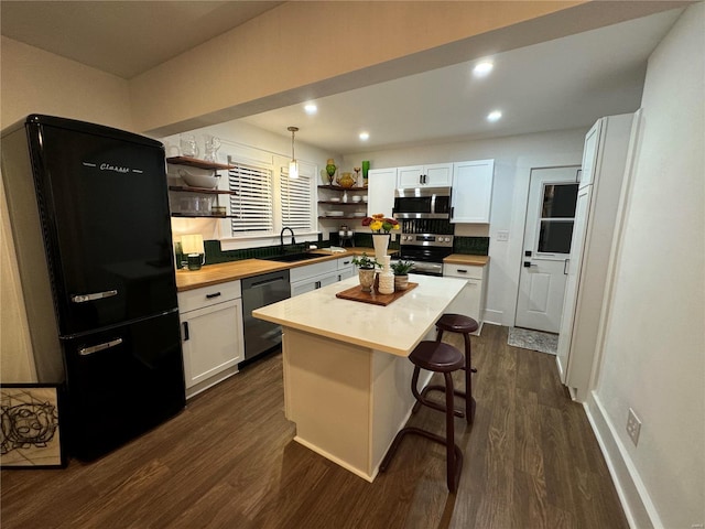 kitchen with white cabinets, appliances with stainless steel finishes, a kitchen island, and pendant lighting