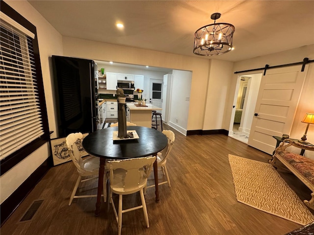 dining room featuring a barn door, dark hardwood / wood-style floors, and an inviting chandelier