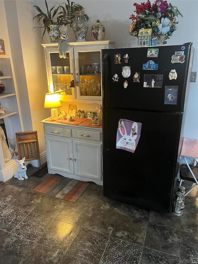 bar with white cabinetry and black fridge