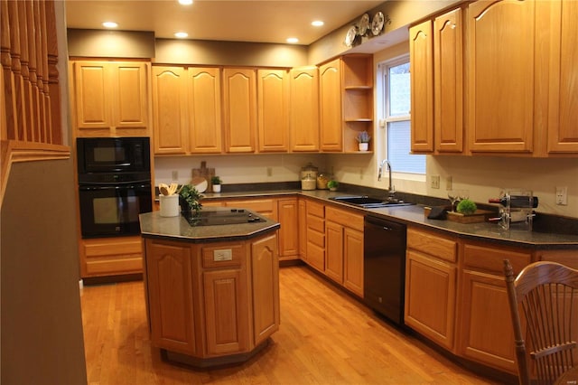 kitchen with light hardwood / wood-style flooring, a kitchen island, black appliances, and sink