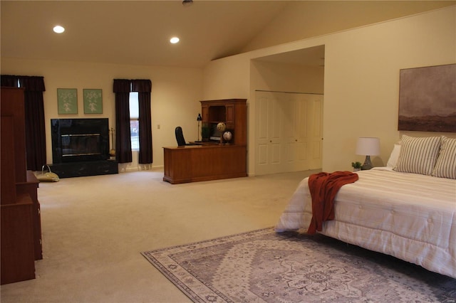 bedroom featuring carpet, vaulted ceiling, a closet, and a premium fireplace