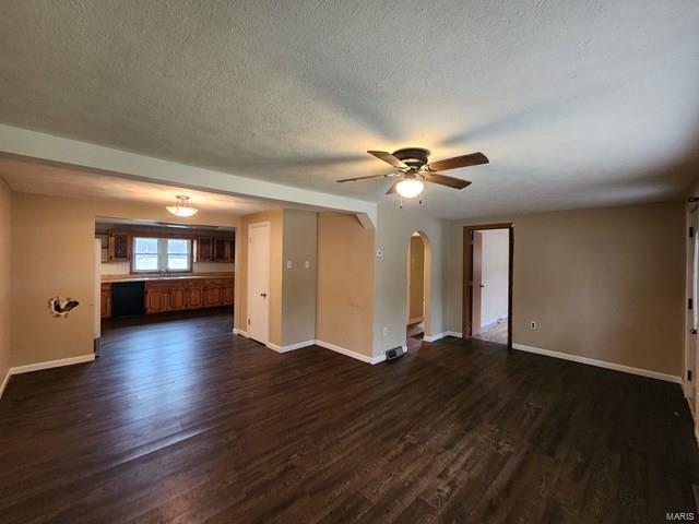 unfurnished living room featuring a textured ceiling, dark hardwood / wood-style flooring, and ceiling fan