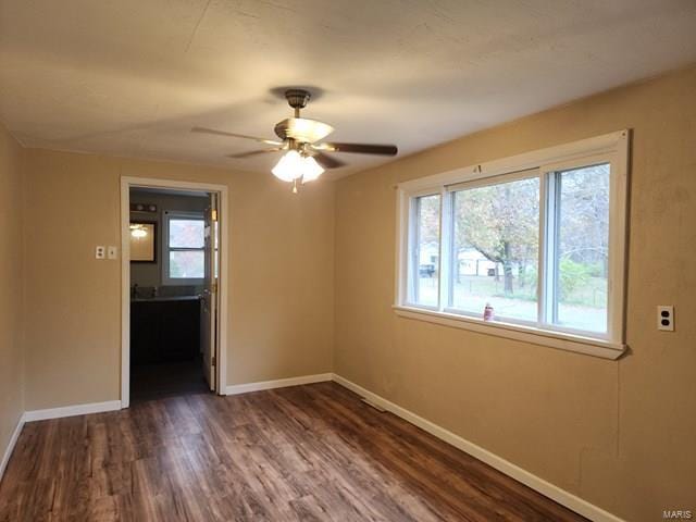 spare room featuring plenty of natural light, dark wood-type flooring, and ceiling fan