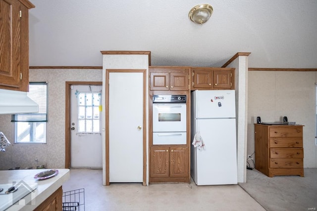 kitchen with light carpet, a textured ceiling, white appliances, vaulted ceiling, and crown molding