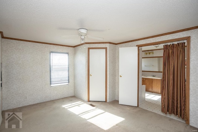 unfurnished bedroom featuring a textured ceiling, a closet, crown molding, and ceiling fan