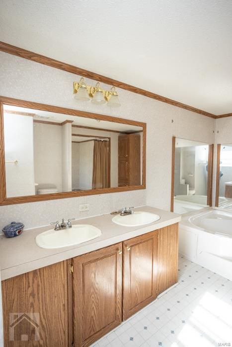 bathroom with a washtub, vanity, toilet, and ornamental molding