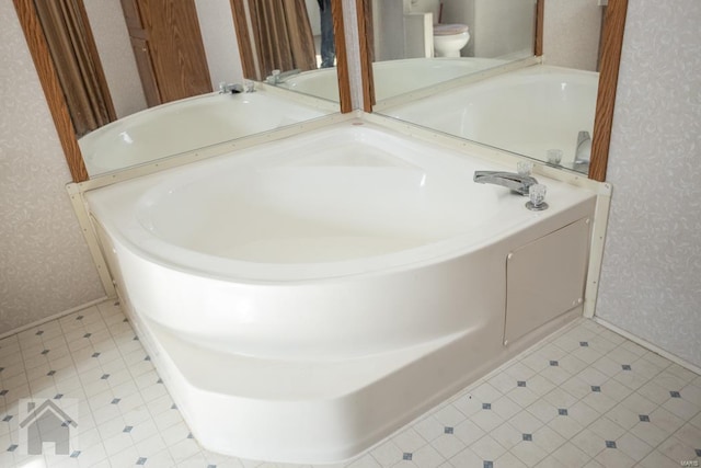 bathroom with a washtub and toilet