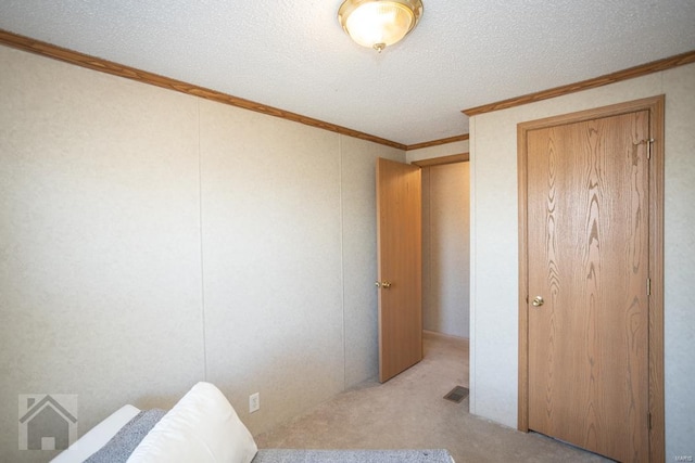 bedroom with light colored carpet, ornamental molding, and a textured ceiling