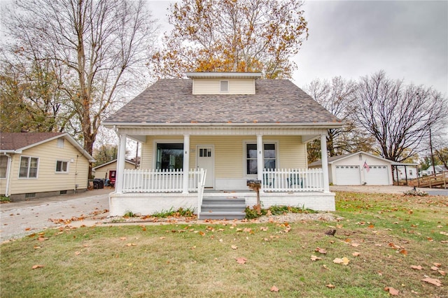 bungalow-style home with an outbuilding, covered porch, a front yard, and a garage