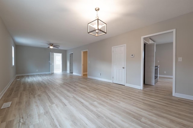 spare room featuring ceiling fan with notable chandelier and light hardwood / wood-style flooring