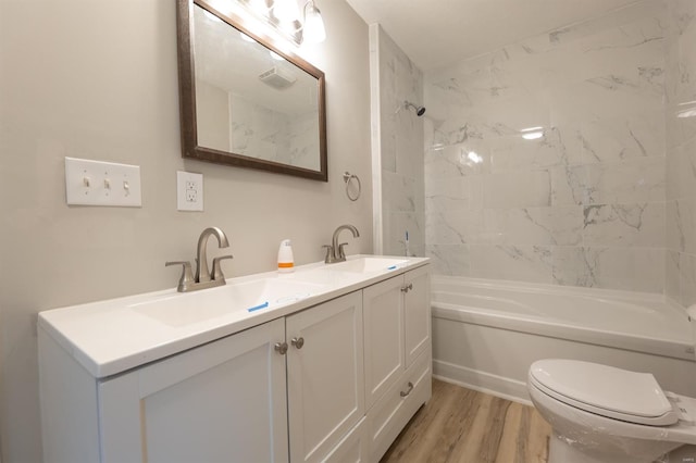 full bathroom featuring toilet, hardwood / wood-style floors, vanity, and tiled shower / bath