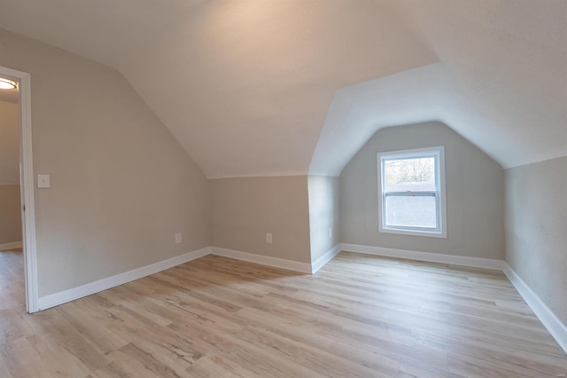 additional living space with vaulted ceiling and light hardwood / wood-style flooring