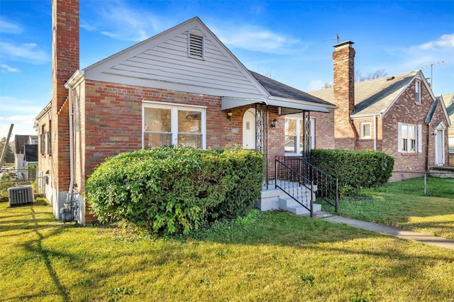 bungalow-style home featuring cooling unit and a front yard