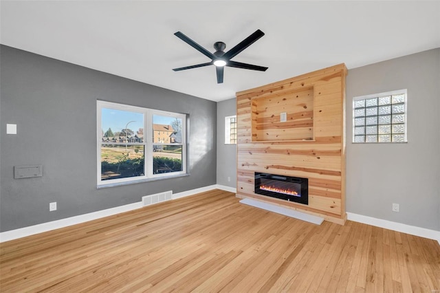 unfurnished living room featuring plenty of natural light, ceiling fan, and light hardwood / wood-style flooring