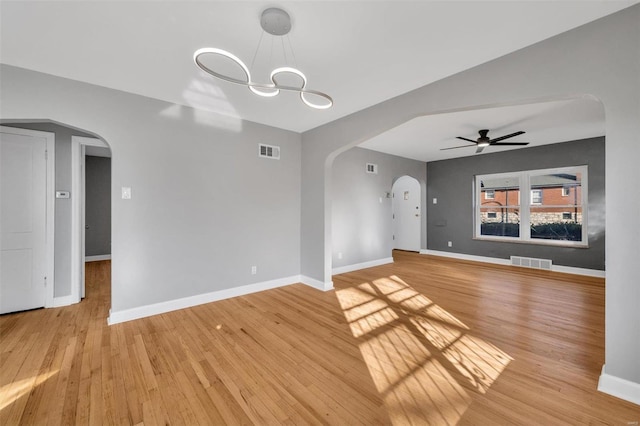 unfurnished living room featuring light hardwood / wood-style flooring and ceiling fan with notable chandelier