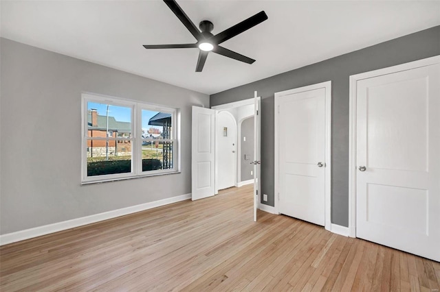 unfurnished bedroom with ceiling fan, light hardwood / wood-style floors, and two closets