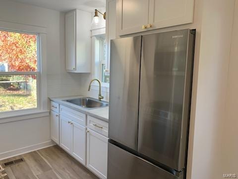 kitchen with white cabinets, sink, and stainless steel refrigerator