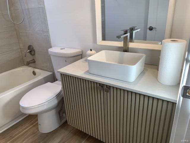 full bathroom featuring vanity, tiled shower / bath combo, hardwood / wood-style flooring, and toilet