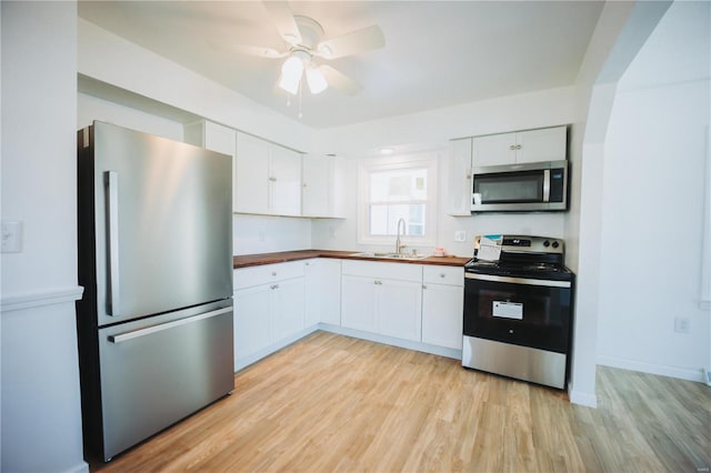 kitchen featuring appliances with stainless steel finishes, ceiling fan, sink, light hardwood / wood-style flooring, and white cabinets