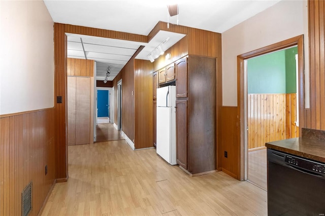 kitchen with dishwasher, white fridge, light hardwood / wood-style flooring, and wooden walls