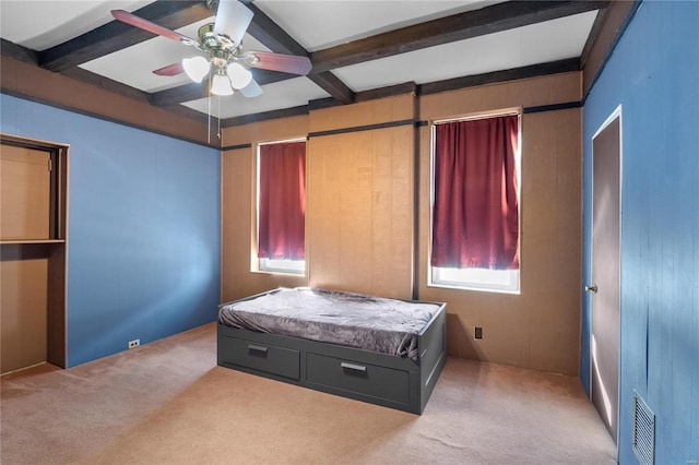 carpeted bedroom featuring beamed ceiling, ceiling fan, and wooden walls