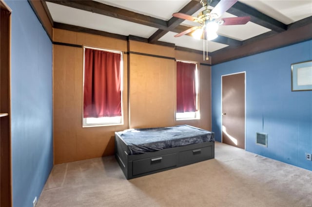 carpeted bedroom with ceiling fan, wooden walls, beamed ceiling, and coffered ceiling