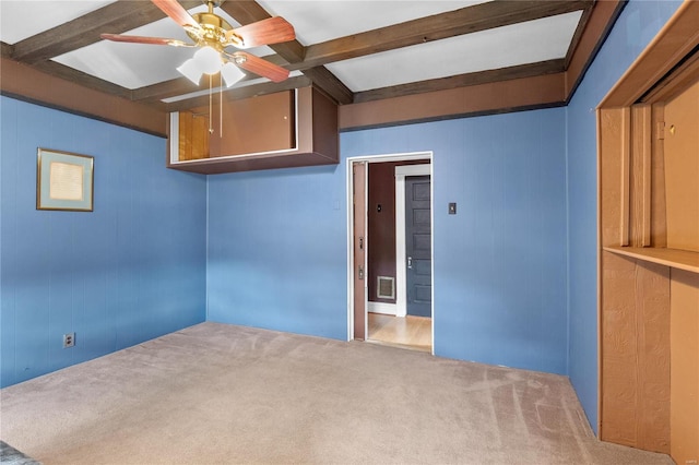 spare room with carpet flooring, ceiling fan, beamed ceiling, and wood walls